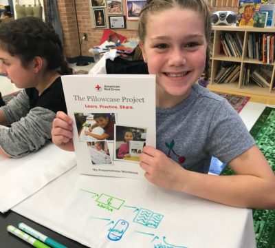 A little girl holding up her Pillowcase Project workbook.